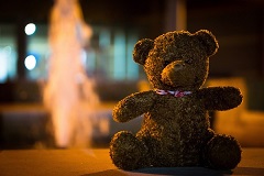 a teddy bear sitting in front of a fountain